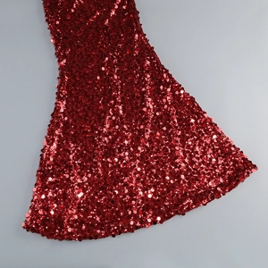Détail d'une robe rouge à paillettes montrant le tissu brillant et la coupe évasée