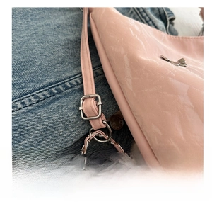 Detail of pink patent leather handbag featuring metal adjustment buckle and chain strap