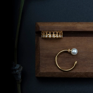 Close-up of gold-plated heart ring and pearl cuff on a professional dark display