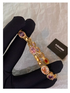 Detail of elegant gold bracelet featuring colorful oval gemstones and cubic zirconia halos