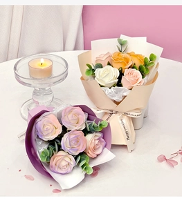 Detail of soap flower bouquet with roses, ribbons and a candle in a gift setting