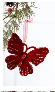 Detail of red velvet Christmas butterfly ornament with gold glitter on pine branch