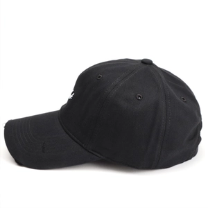 Detail of white letter embroidery and distressed brim on a black cotton baseball cap