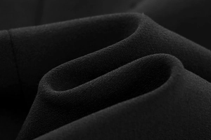Detail of high-density black knit fabric texture with elegant draping and premium finish