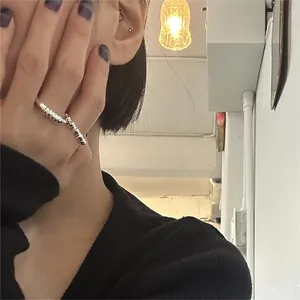 Detail showing a minimalist twisted silver 925 ring worn on a finger in daily setting