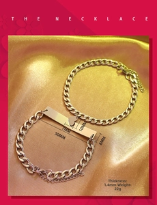 Close-up of polished stainless steel Cuban link bracelet with heart charm on silk