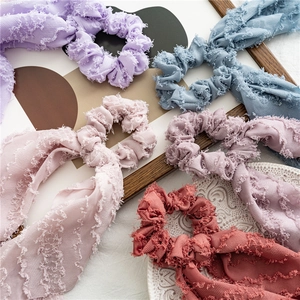 Assorted textured fabric scrunchies with bow tie detail in multiple pastel colors