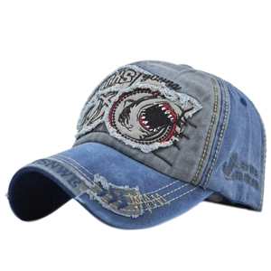 Detailed embroidery of a shark and distressed patches on a washed denim baseball cap