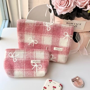 Detailed view of pink and white checkered plush makeup bags with bow embroidery