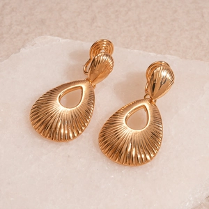 Macro detail of golden teardrop earrings featuring intricate radial textured patterns