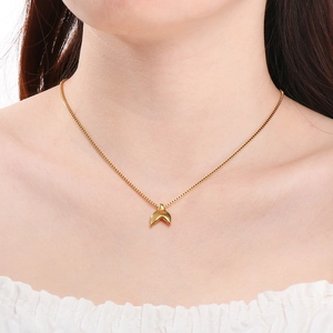 Detail of a minimalist golden fishtail pendant necklace worn on a model neckline