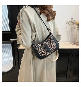 Detail of leopard print underarm bag with black leather trim and golden metal buckle