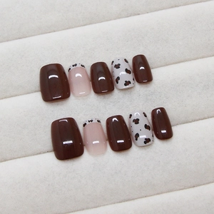 Chocoladebruine en luipaardprint kunstnagels op een wit pluchen dienblad