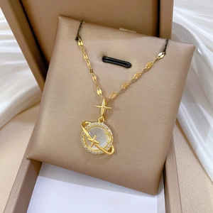 Macro view of gold planet pendant with cat eye stone and diamonds on silk background