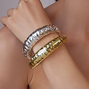 Close-up of gold and silver chunky hammered open bangles on a woman's wrist