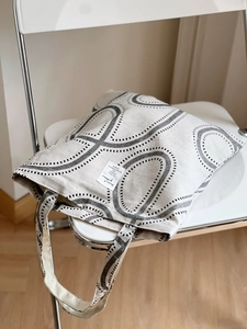 Detail of geometric circle print tote bag on white chair in a minimalist home setting