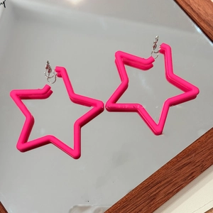 Gros plan de boucles d'oreilles étoiles roses en acrylique sur un fond réfléchissant