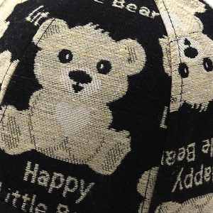 Close-up of black baseball cap fabric with Happy Little Bear embroidery detail