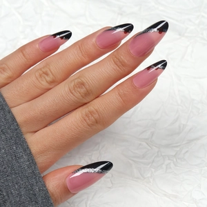 Long almond press-on nails with creative black French tips and silver glitter accents