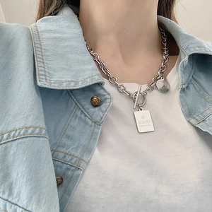 Detalle del collar de acero inoxidable plateado con cierre OT en modelo con vaqueros