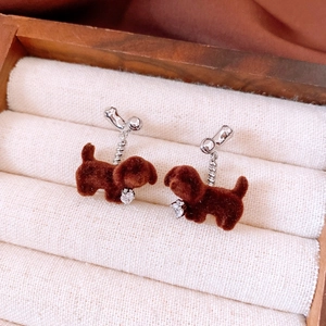 Close-up of cute flocked brown puppy earrings with sparkling heart-shaped zircon charms