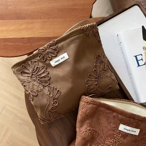 Detailed embroidery and suede texture on vintage camel makeup bags with brand label