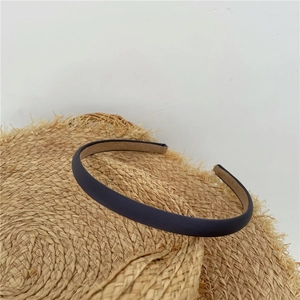Close-up of navy blue matte fabric headband placed on a straw hat with a white background