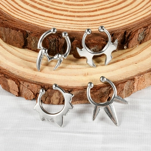 Detailed view of silver non-pierced U-shaped septum rings with spikes on wood texture