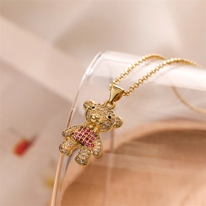 Detailed close-up of a gold bear pendant necklace with sparkling pink and white crystals
