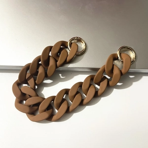 Macro detail of brown matte acrylic chain strap with gold round spring buckles