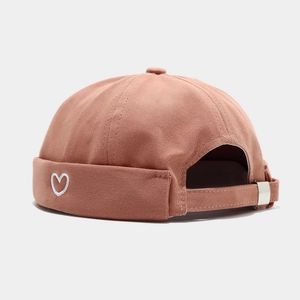 Detail of a dusty pink Miki Hat featuring a white heart embroidery and metal buckle adjuster