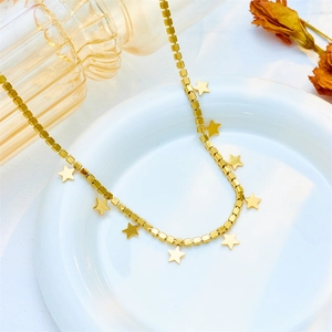 Star charm necklace set in gold finish displayed on white ceramic plate with dried flowers