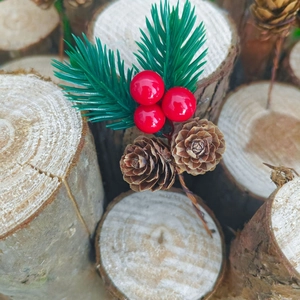 Close-up of Christmas pine needle branch with red berries and natural pinecones on wood