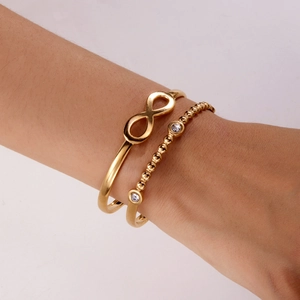 Detail of gold-plated infinity cuff and rhinestone beaded bracelet set on female wrist