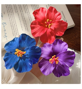 Macro shot of colorful hibiscus flower hair clips in red, royal blue, and deep purple colors