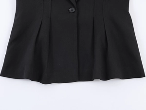 Detail of black blazer featuring ruffled peplum hem and single button closure detail