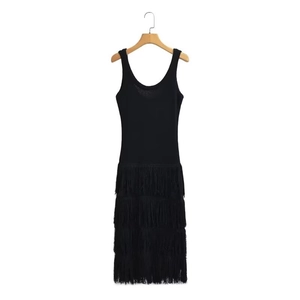 Détail d'une robe noire sans manches en tricot avec des franges multicouches sur fond blanc