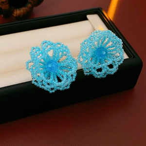 Detail of blue beaded flower earrings with micro weaving on a jewelry display box