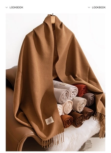 Close-up of assorted earth-tone imitation cashmere scarves with fringe and wood hanger
