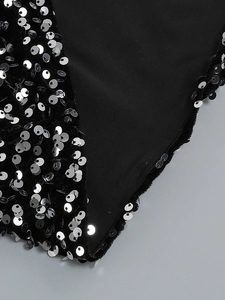 Détail macro de sequins argentés cousus sur le tissu noir d'une robe de soirée