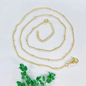Close-up of gold plated beaded chain with lobster clasp and adjustable extension on white