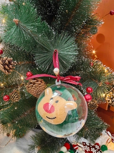 Grüne Weihnachtssocke mit Rentier in transparenter Kugel am festlichen Weihnachtsbaum