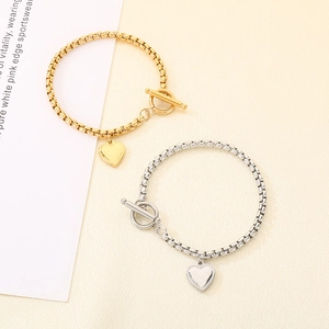 Dettaglio di bracciali con ciondolo a cuore oro e argento con chiusura a T e catena veneziana