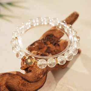 Detailed macro view of white crystal beads with gold heart charm on a wood stand