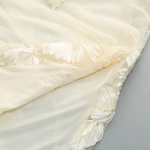 Close-up of cream halter dress featuring floral lace embroidery and sheer mesh layers