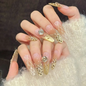 Elegant stiletto press-on nails with golden gradient, glitter, and luxury rhinestones