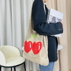 Detailed close-up of knitted cherry pattern on a beige cotton tote bag with mesh texture