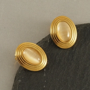 Close-up of vintage gold earrings with champagne cat eye stones on dark stones
