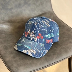 Close-up of blue denim baseball cap featuring colorful floral prints and textured fabric