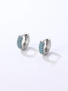 Gros plan détaillé des boucles d'oreilles huggie argentées serties de pierres turquoise